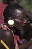 A maasai man at an intiation ceremony for the Moran coming into manhood with ears stretched with a pill container.