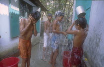 Street boys in a refuge home bathing using buckets and cups.