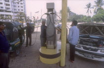 Men with car and LNG three wheeler taxi filling up on environmentally sound Liquid Natural Gas at one of  the few filling stations in Dhaka.