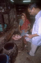 Women selling freshly slaughtered chicken pieces to a male buyer.