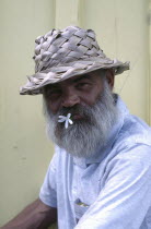 Portrait of a man with a flower in his mouth wearing a straw hat
