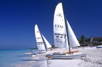 View along white sandy beach with sail boats at the waters edge