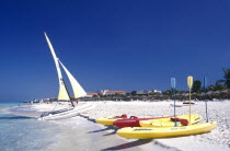 View along golden sandy beach with kayaks and sail boats at the waters edge