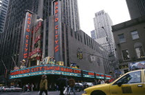 City street scene with Radio City advertising Christmas lineup and yellow cab in the foreground