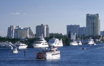 View of Paddle steamer sailing up the intra coastal waterway passing moored yachts with the city skyline beyond