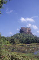 View towards huge monolithic rock site of fith century citadel.  Also called Lion Rock.  Lake with water lillies in foreground.