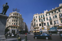 Midan Talaat Harb.  Traffic on city road lined by cream coloured buildings with green shutters and curved facades