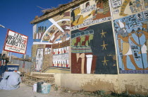 Painted mural on exterior wall of alabaster shop with man crouched down beside Pepsi sign outside.