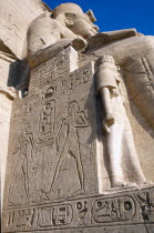 Sun Temple of Ramses II.  Part view of one of the colossi of Ramses II flanking entrance to temple showing wall with relief carving and hieroglyphics.