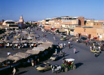 Djemaa El Fina Square. View over busy market square lots of people at stalls and buildings behind.