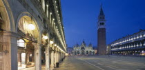 Piazza San Marco.  View along the colonnaded Procuratie Vecchie towards the Basilica di San Marco and the Campanile illuminated at dusk.