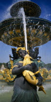 Place de La Concorde.  Detail of fountain with sculpted female figure holding a golden fish spouting water.