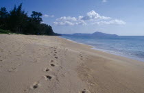 View north west along empty sandy beach with lines of footprints in the foreground