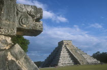 Stone carving on the Platform of the Eagles in the foreground with El Castillo behind.