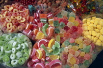 Close view of open topped bags of colourful sweets for sale.