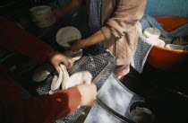 Preparation of tortillas at tortilla bakery or Tortilleria.  Cropped view of people at work.