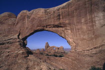 View through natural rock archway toward rock formations