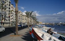 View along the esplanade lined with palms and fishing boats pulled ashore.