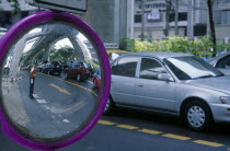 Road side mirror reflecting traffic policeman with passing traffic.