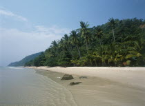 White Sand Beach  Haad Sai Khao. View along sandy shore with lush green trees growing inland.