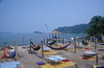 People lying in hammocks on a wooden platform built over rocks on Aow Bai Lan Lonely Beach