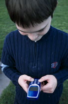 Close up of a boy holding a blue mobile phone with thumbs on the dialing pad.