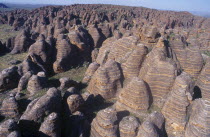 View over rounded rock towers striped in alternate bands of orange silica and black lichen.