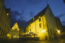 Exterior of cafe with tables and chairs on cobbled street outside at night.