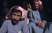 Two seated men wearing traditional red and white checked headscarves  gutras or kiffeiyas.