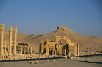 View towards Monumental Arch comprising of high central arch flanked by a lower arch on each side with the Arab Castle or Qalaat Ibn Maan on the hilltop behind.