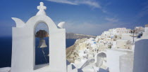 Detail of white painted church bell tower with white painted hill town beind.