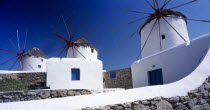 Three white painted windmills against blue sky.