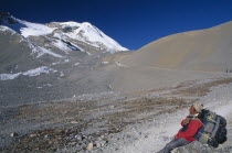 Porter carrying large back pack resting on the approach to Thorung La pass.