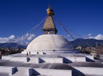 Bodhnath stupa hung with prayer flags with visitors on surrounding steps.