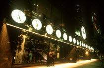 Tourneau Store on West 57th Street at night with row of illuminated clock faces giving the correct time worldwide across the exterior facade.