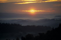 Sunrise through mist over wooded hillside.European Italia Italian Southern Europe Scenic Toscana Tuscan