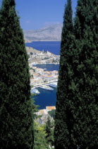 Gialo.  The town and harbour partly viewed between trees in the foreground.