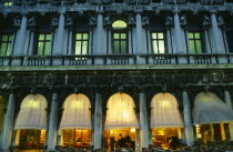 Italy, Veneto, Venice, Piazetta San Marco, Cafe at night, detail of facade showing balcony, windows and lighted interior.