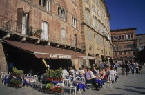 The Piazza del Campo with people sitting at tables under umbrellas outside a restaurant