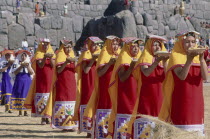Parade of women offering  food at Inti Raymi.  Inca walls behind.