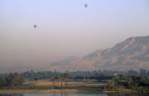 Valley of the Kings with two hot air balloons over the river Nile at sunrise