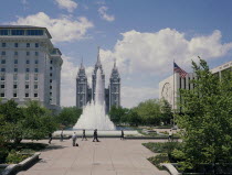 The Mormon Temple beyond the fountain in the gardens with the US flag flying from a flagpole