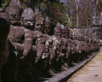 Angkor Thom.  Close up of ancient stone figures lining causeway leading to gateways or gopuras.