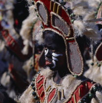 Young girl in costume at Ati-Atihan festival with a black painted face and wearing a headdress