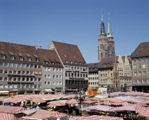 The Hauptmarkt. Market stalls with red and white striped canopies in the square beneath the twin spired church