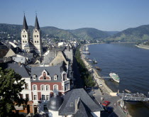 Town beside River Rhine. Building with twin towers. Boats moored at pontoons.