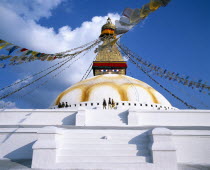 Bodnath Stupa.  White painted steps leading to dome of stupa painted with eyes and hung with prayer flags.