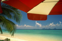Koh Kraddan in the distance across clear calm blue sea seen from beneath an umbrella on the beach