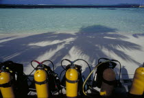 Looking out to sea with scuba diving tanks on the beach in the shadow of coconut palm trees