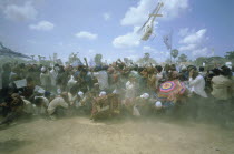 UN helicopter carrying Prince Ranaridth Sihanouk during the 1993 elections takes off above a crowd of his supporters leaving them in a dust storm